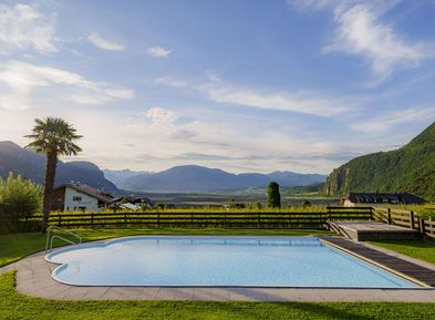Piscina all'aperto con prato e vista sulle Dolomiti agli appartamenti Wieserhof Andriano