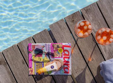 Aperitivo Aperol Spritz con rivista, occhiali da sole e crema solare a bordo piscina al Wieserhof Andriano